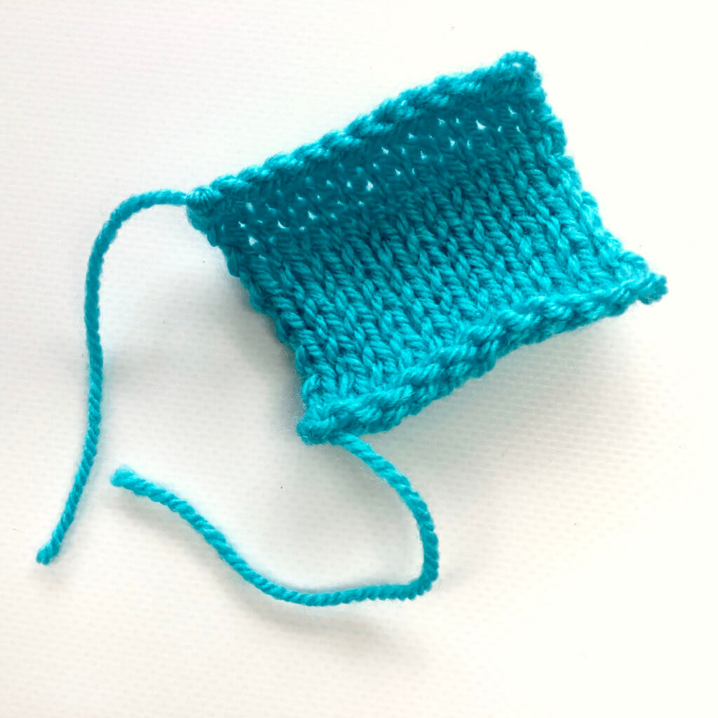 Turquoise knitted swatch in stockinette stitch on a white background.