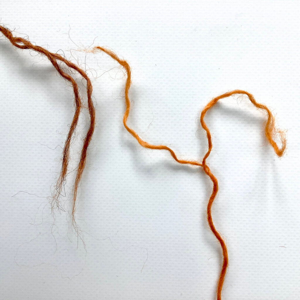 2 yarn ends (1 brown, 1 orange), with the ends teased apart in the 2 plies.