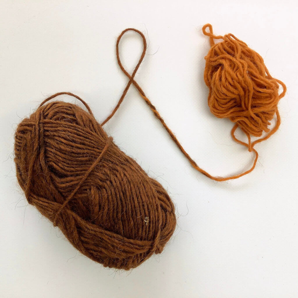 2 balls of yarn (1 orange, 1 brown) joined together on a white background.