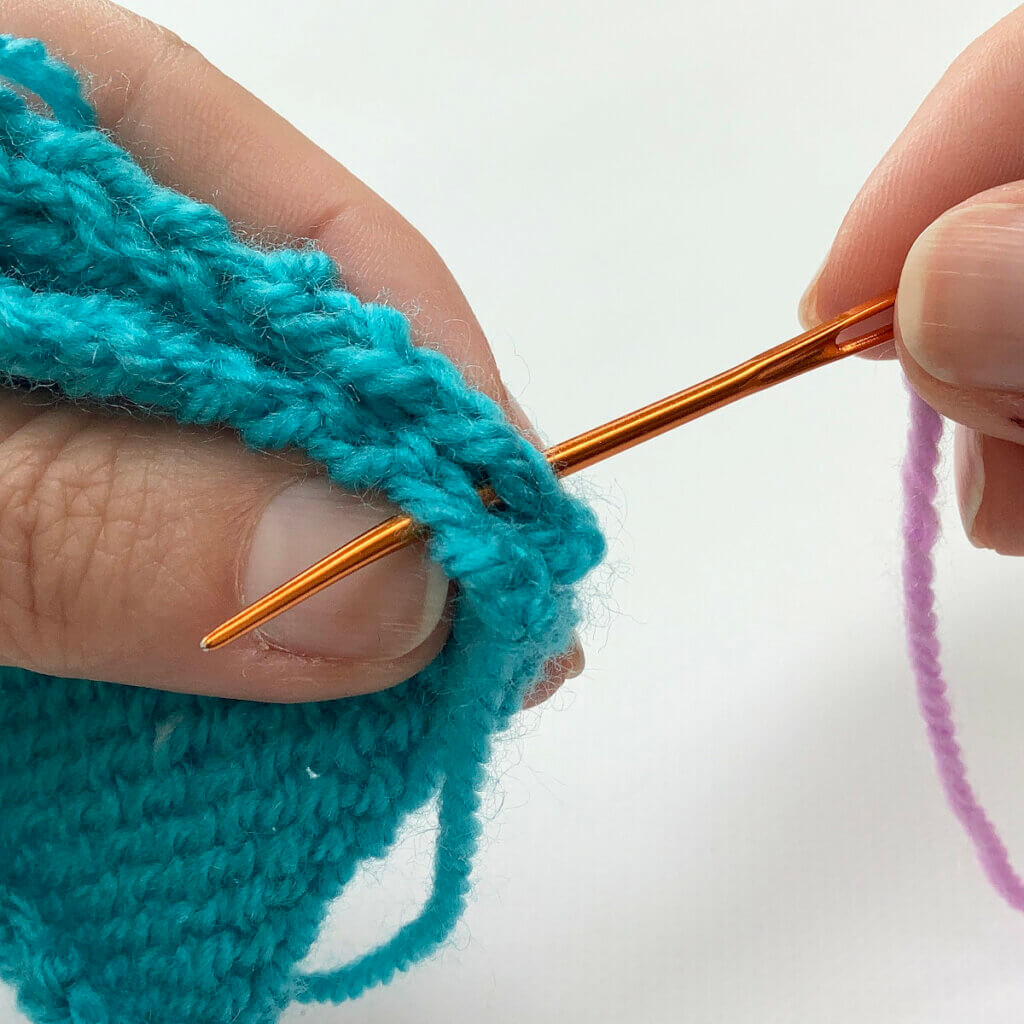 Working a whip stitch seam at the side of a piece of knitted fabric.
