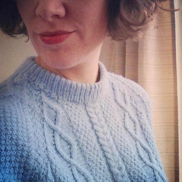 A woman wearing a light blue cablesd sweater