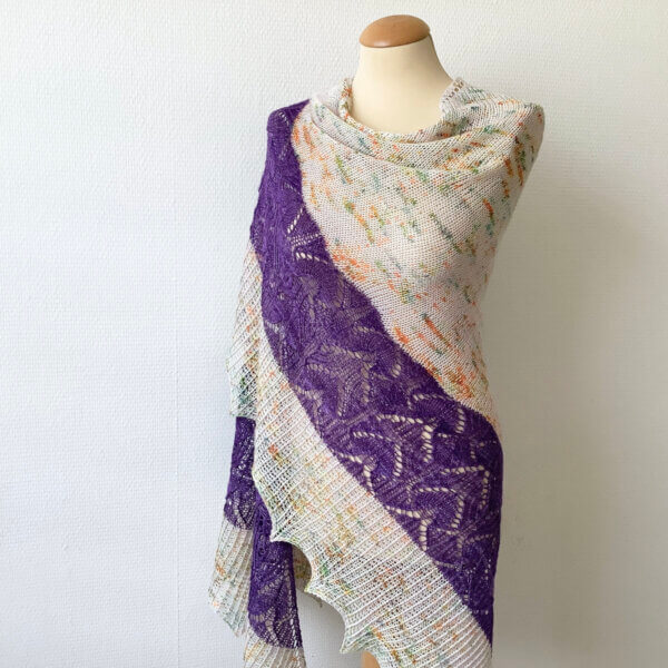 electric violet Electric Violet - A knit shawl in pale pink yarn with multicolored speckles, a lace border in deep purple, followed by an edging in twisted rib. It's shown on a mannequin against a white background.