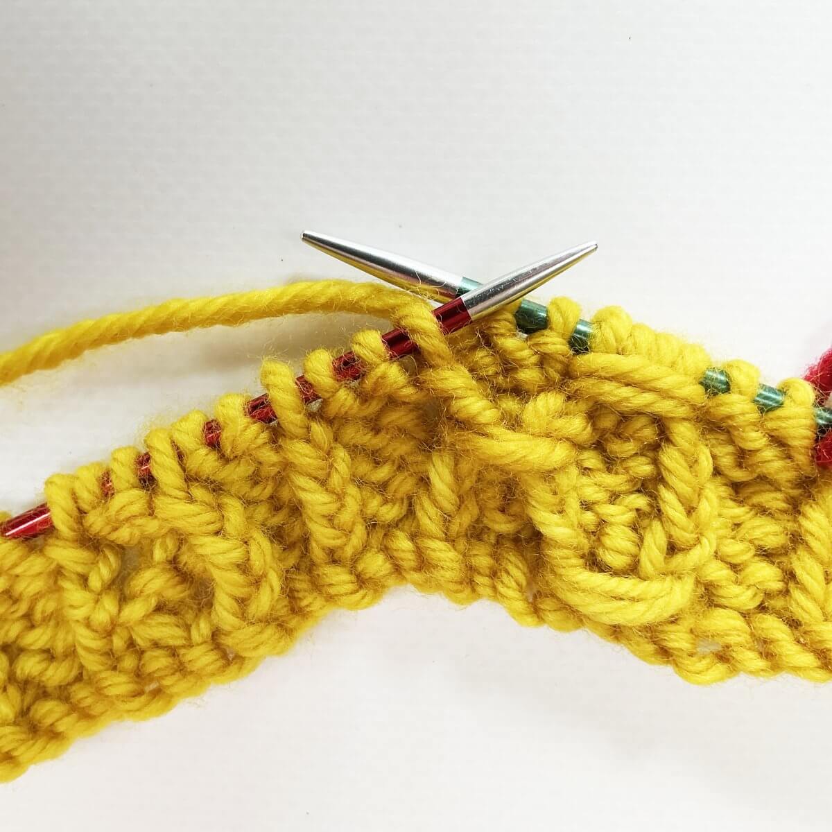 Step 1 of working the (k tbl, p2, k tbl) wrapped twice stitch