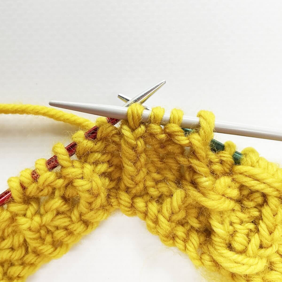 Step 5 of working the (k tbl, p2, k tbl) wrapped twice stitch