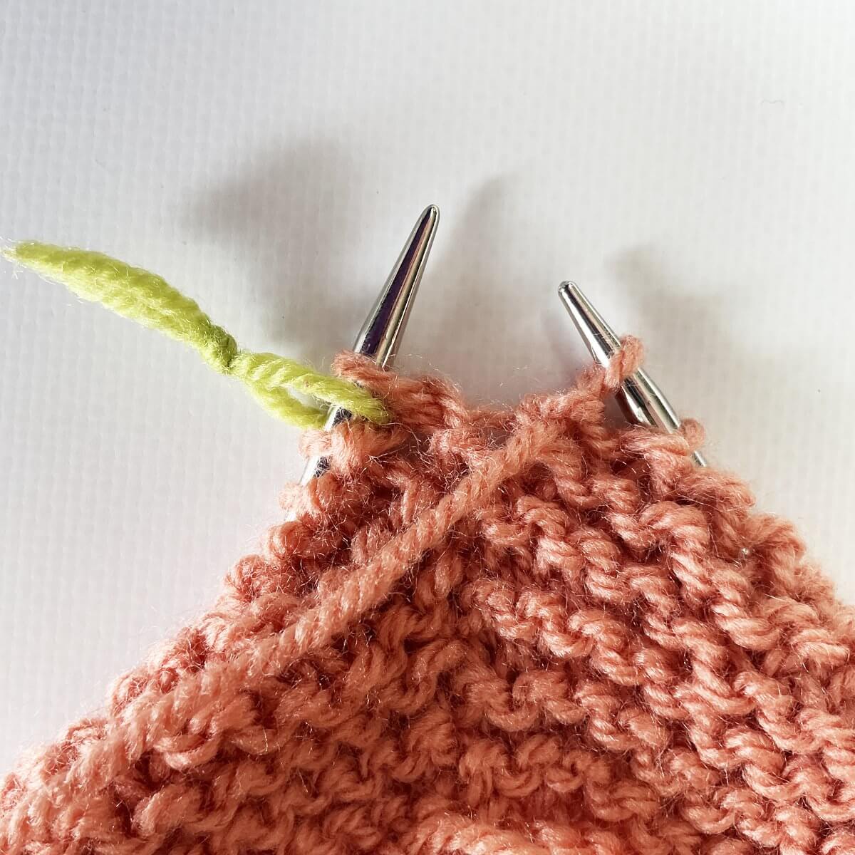 Step 1 of working jog-less garter stitch in the round with the lifted strand & p2tog method